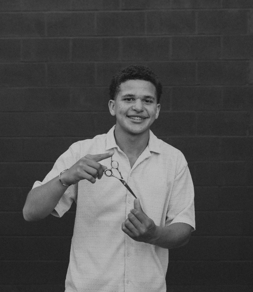 A professional headshot of a student holding scissors.