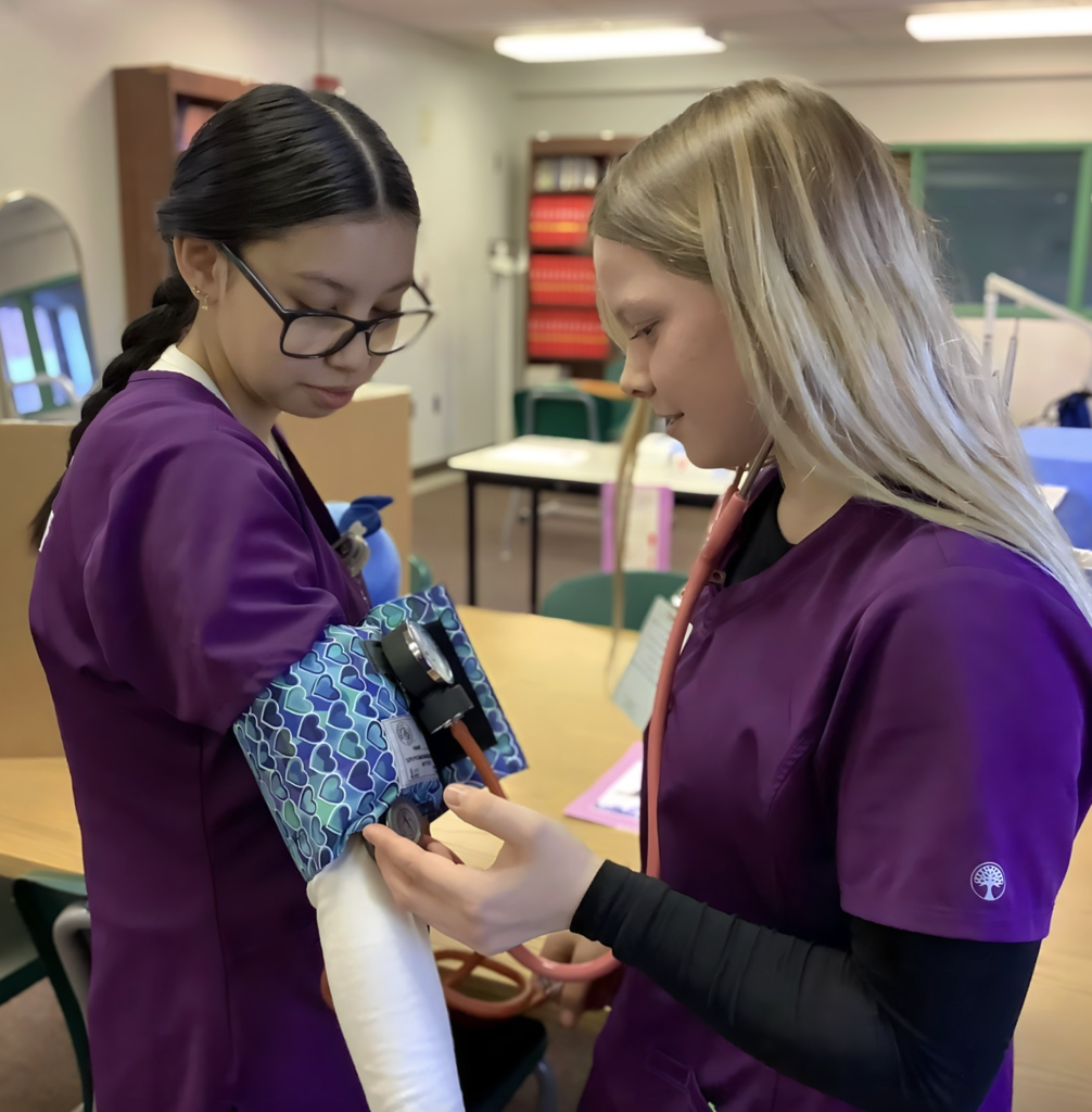 One student checking another student's blood pressure.  
