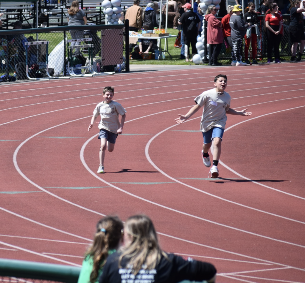Two student-athletes raced down the track during the Special Olympics Track and Field event at Avon Central School, giving their all as classmates, volunteers, and spectators cheered them on from the sidelines.