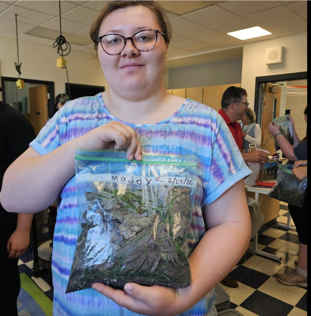 A student displays a composting bag filled with leaves, grass clippings, and other organic materials created during an Ag in the Classroom lesson at the Dansville Campus.