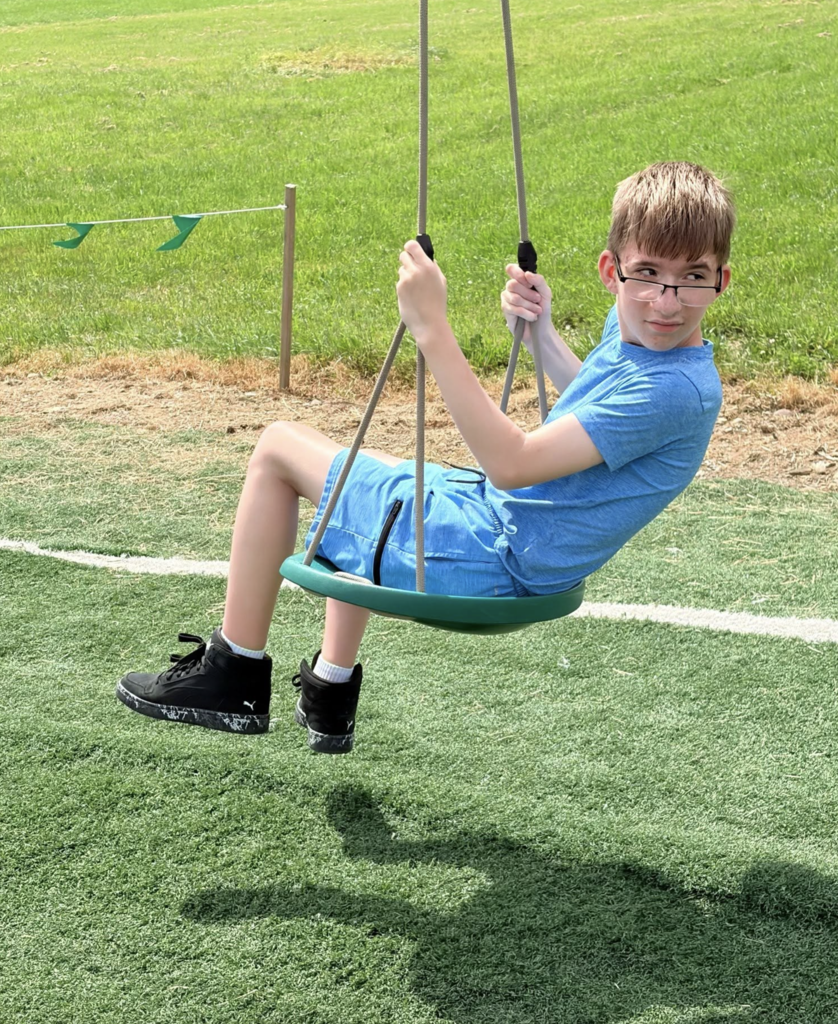 Student looking back while on a tire swing.  