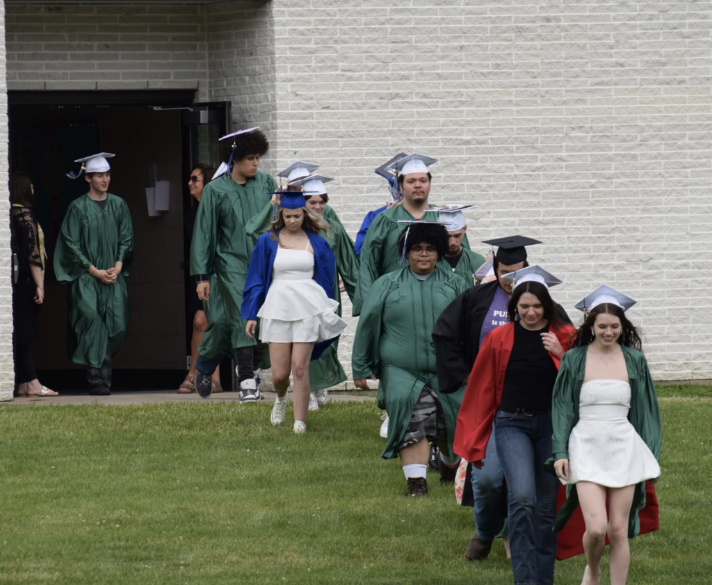 Students in caps and gowns walking out of the building on their way to the graduation ceremony. 