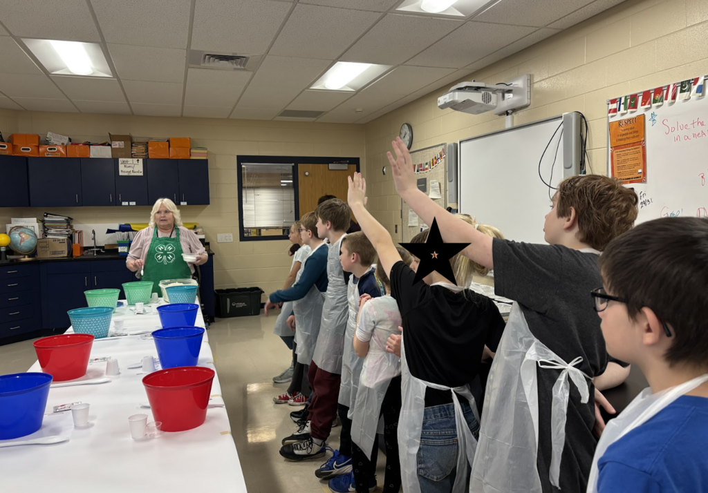 Students with 4H leader raising hands to answer questions