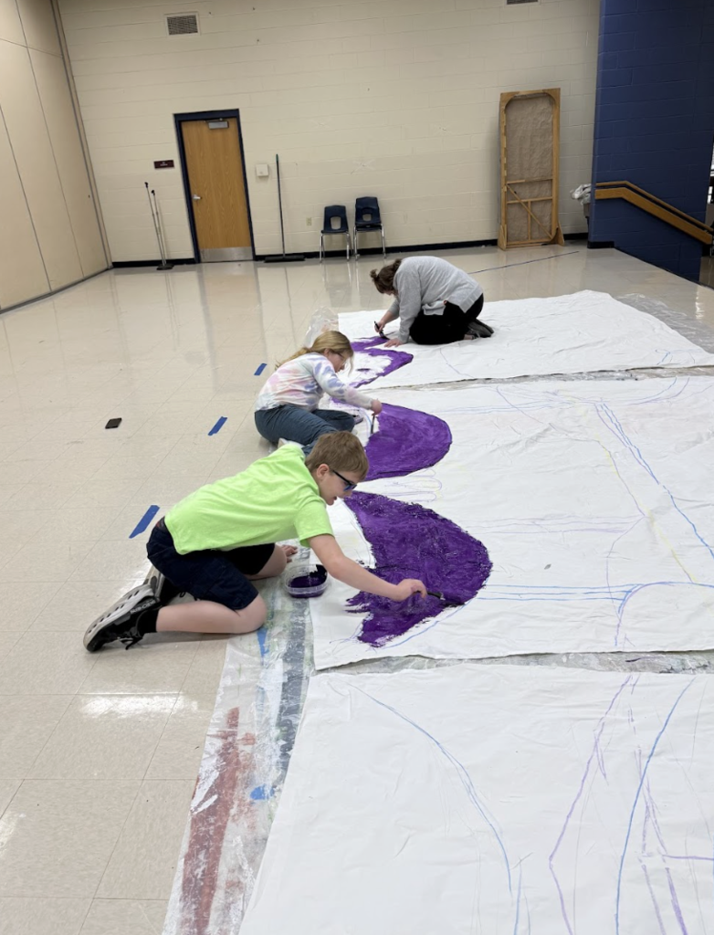 Student and parent painting a set design for Beauty and the Beast show 2
