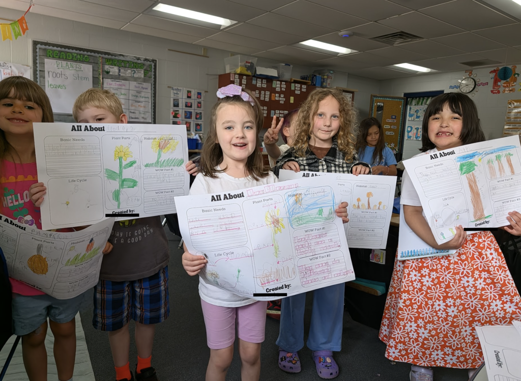 Students showing off their All About Plants worksheets 