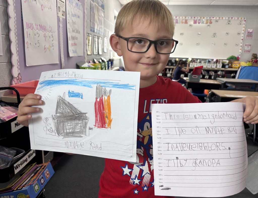 First Grade Student Showing Their Map and Writing Piece