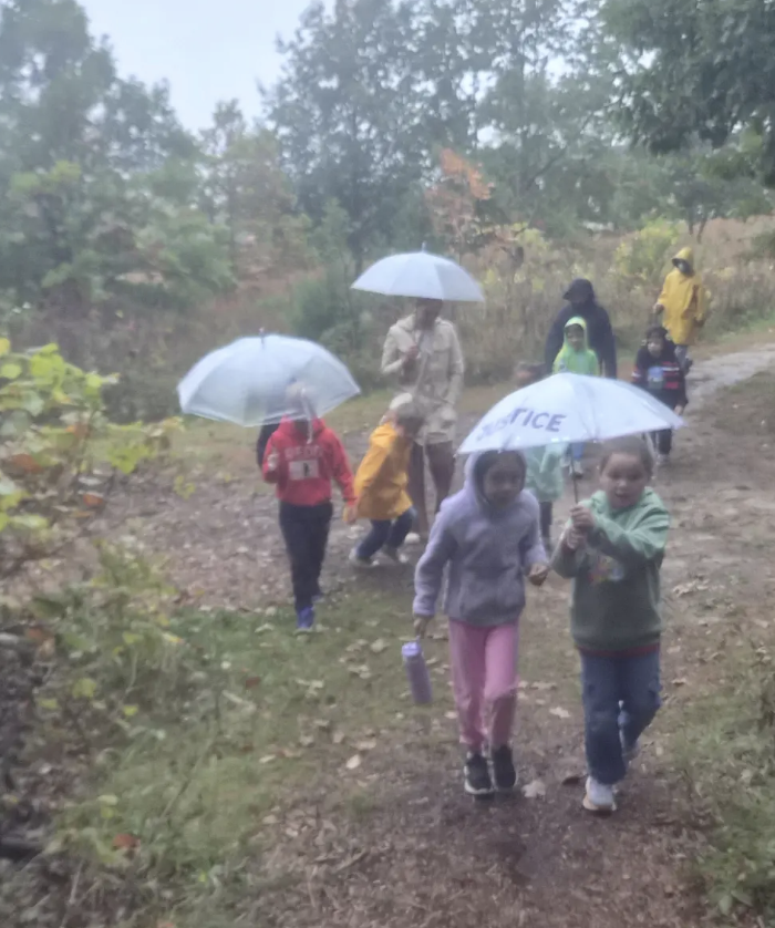 Students walking in the rain with the forest terrian
