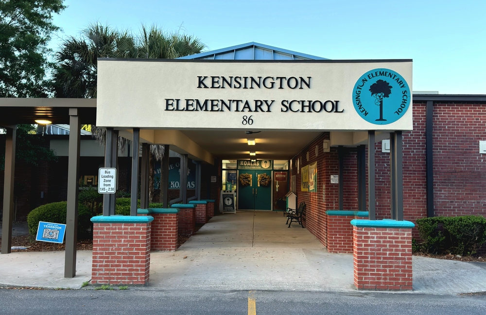 Photo of the front of the school with a new teal circular sign