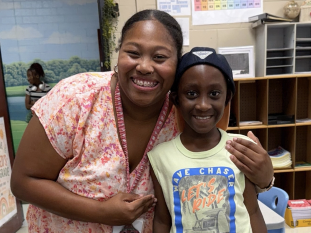 First Grade Teacher welcoming a  student to her class at PHESA. 