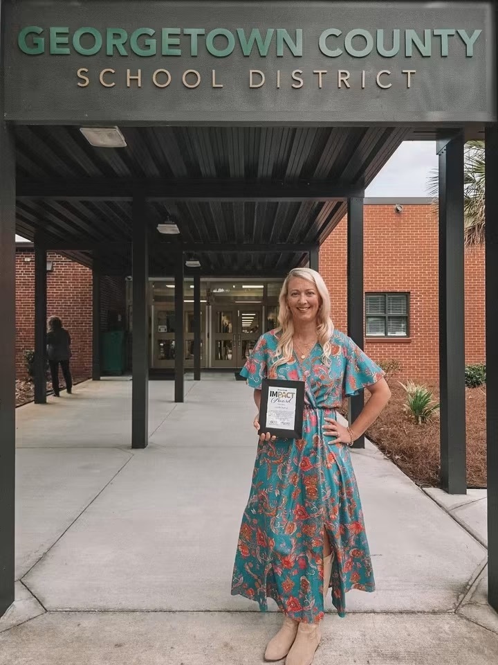 Jennifer Watford stand in front of district office holding a certificate