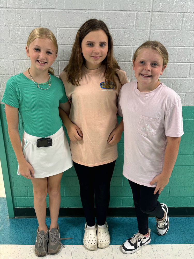 3 Girls standing together at a hallway wall