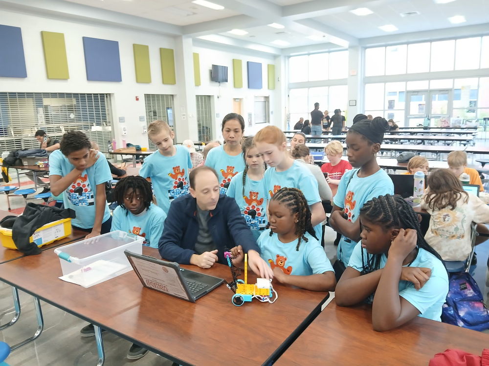 Lego students sitting and standing at a table during event.
