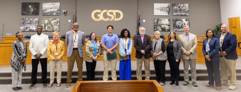 Carvers Bay High's FBLA State Champions (center holding green certificates) pictures with their advisor Mrs. Alston (far left) , the GCSD Board of Trustees, and Assistant Princpal Jenermy Bonser (far right)