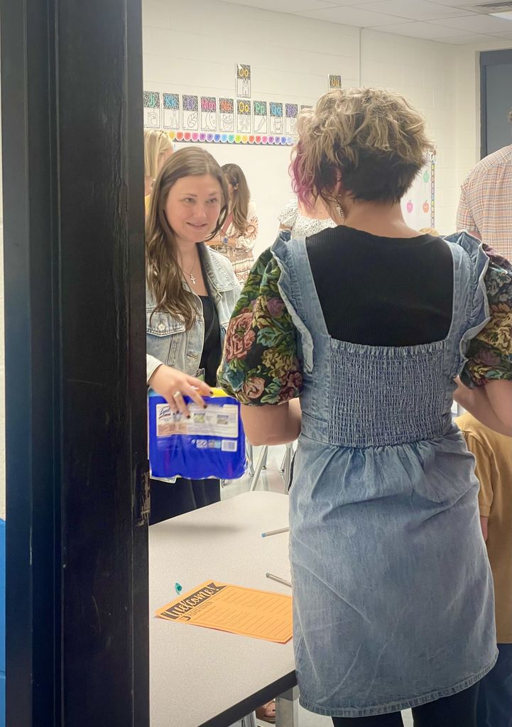 Teacher greating parents at the door of her classroom