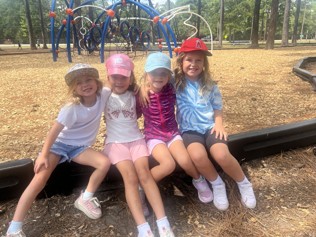 Four young female students sitting together on the playground.