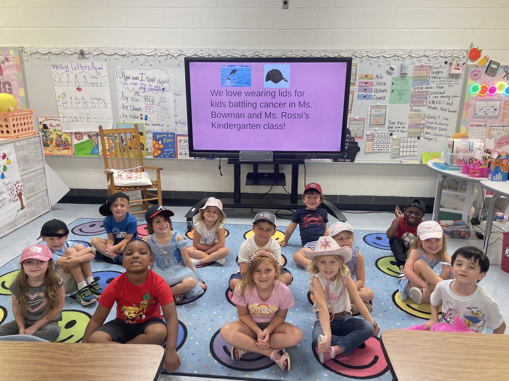 Students sitting on rug in classroom.