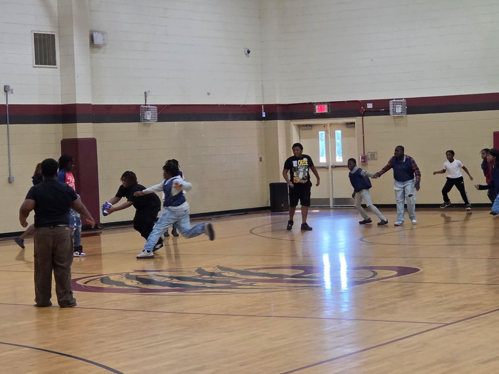 Hello Bear Family! These are pictures of our boys and girls playing in a game of flag football in our gym, hosted by Student Council. In the first picture, Mr. Williams is standing with several children explaining the rules of the game. In the other pictures, the children  are running up and down the courts playing football.