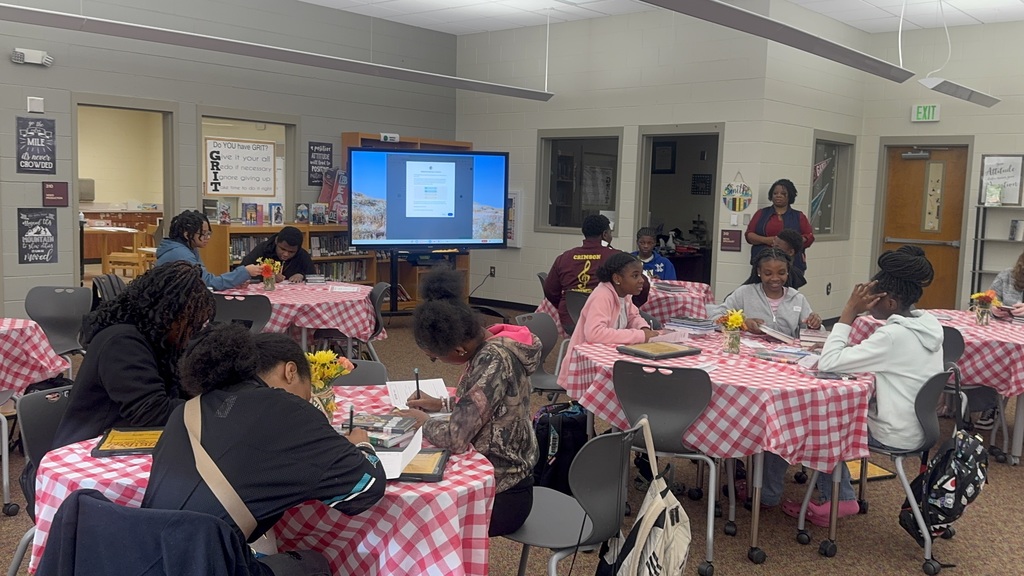 Students sitting at tables and writing about the books they're interested in.