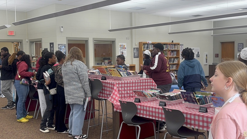 Students standing by table to sample new library books at the Bear Book Buffet.