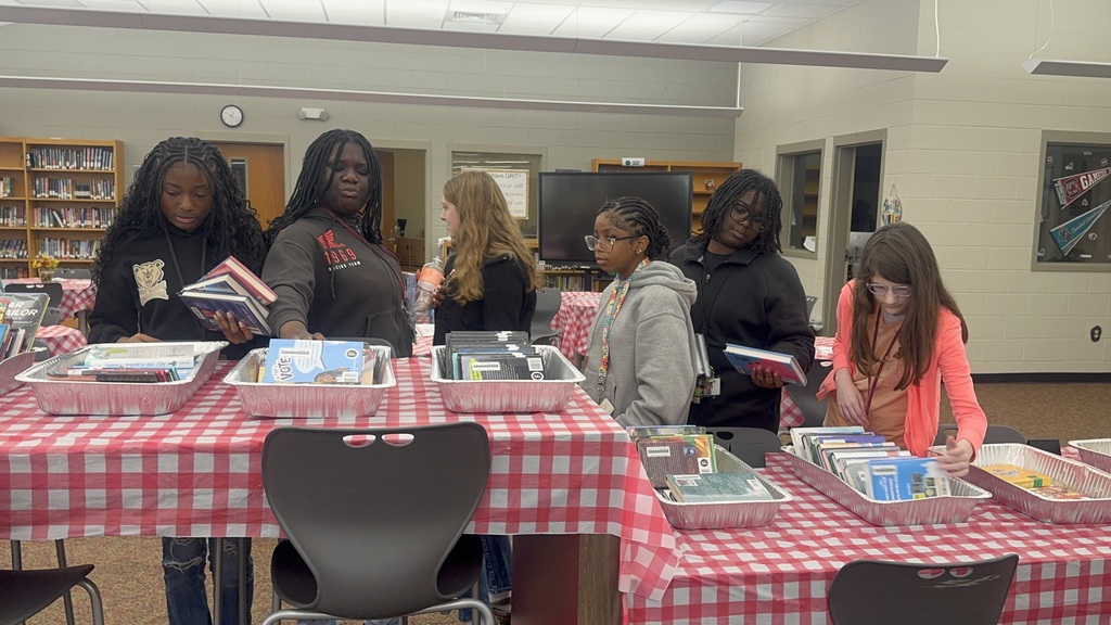 Girls standing and looking through books.