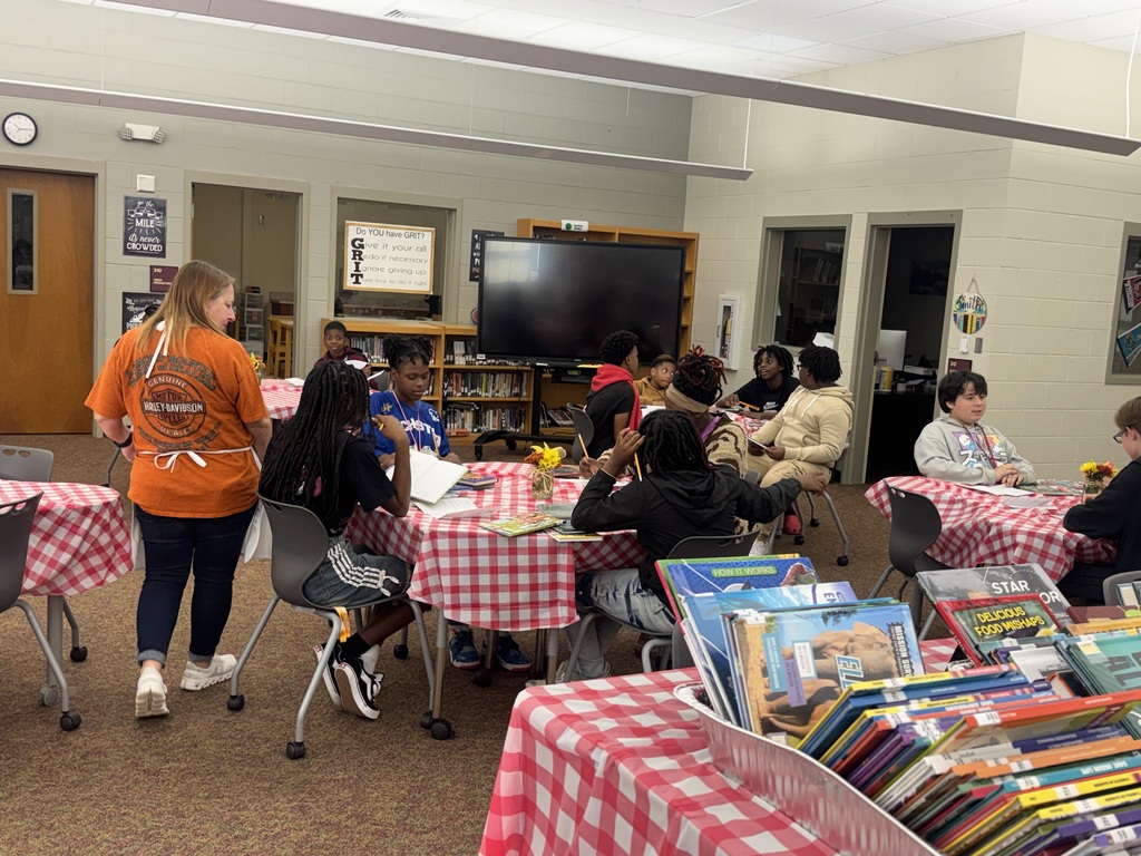 Students sitting at table looking through new books.