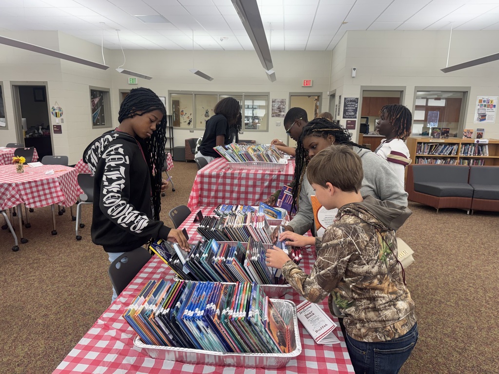Students standing at table looking through new books.