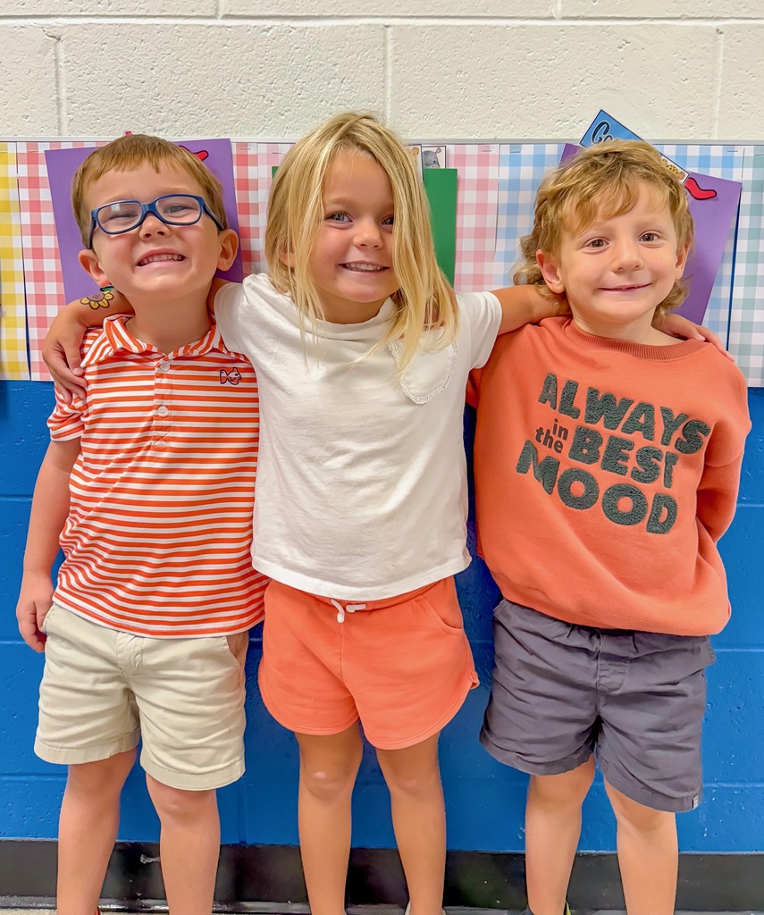 Boys & Girls standing together, most wearing the color orange. 