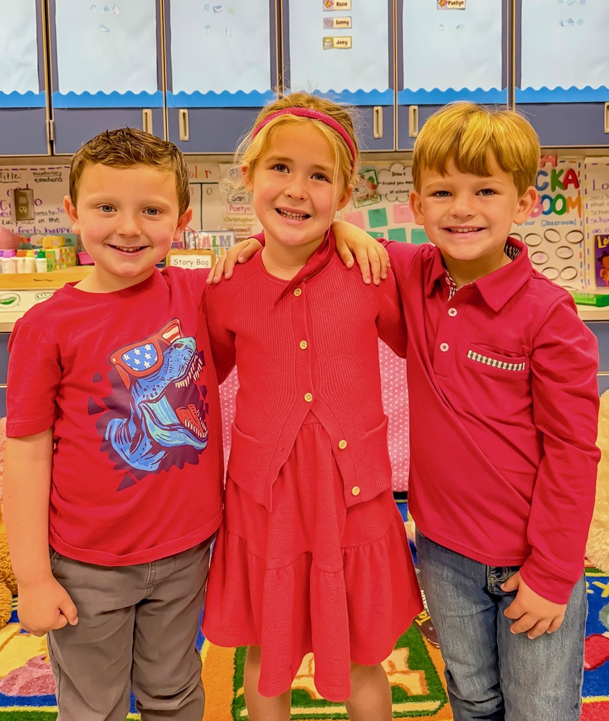 A group of elementary students dressed in red pose together in a classroom for Red Ribbon Week.