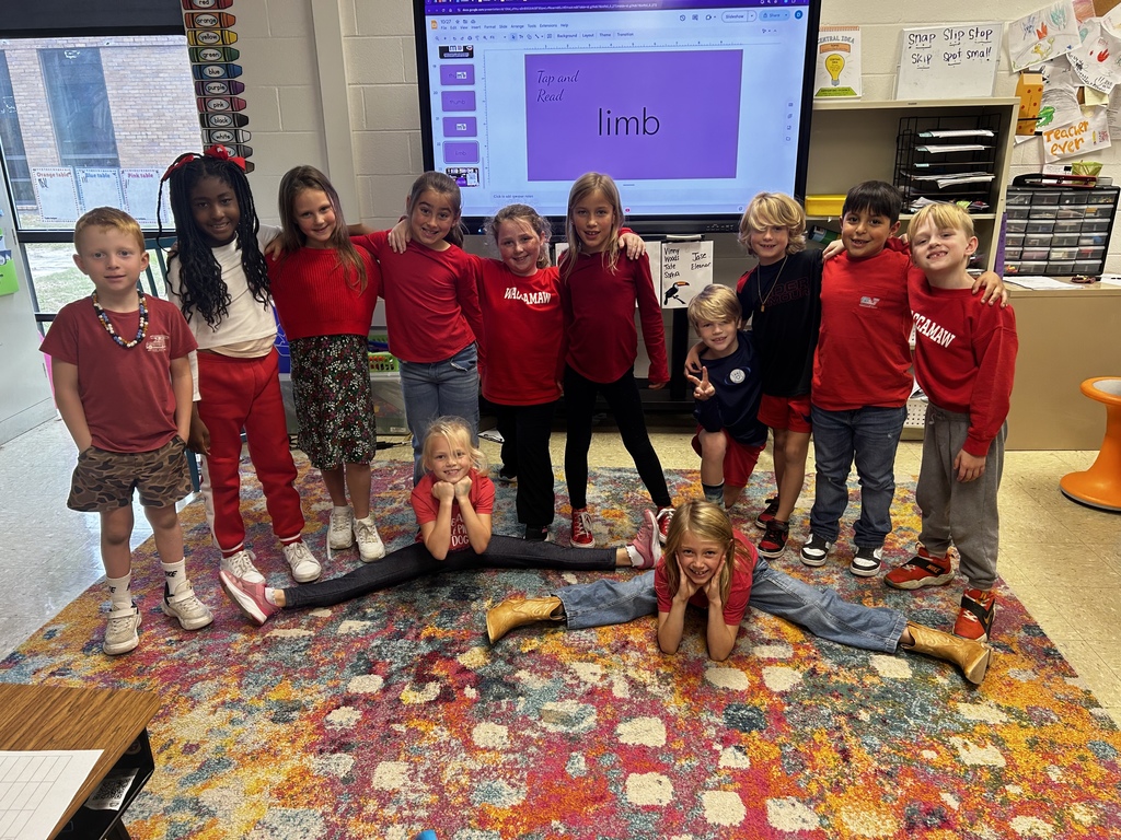 A group of elementary students dressed in red pose together in a classroom for Red Ribbon Week.