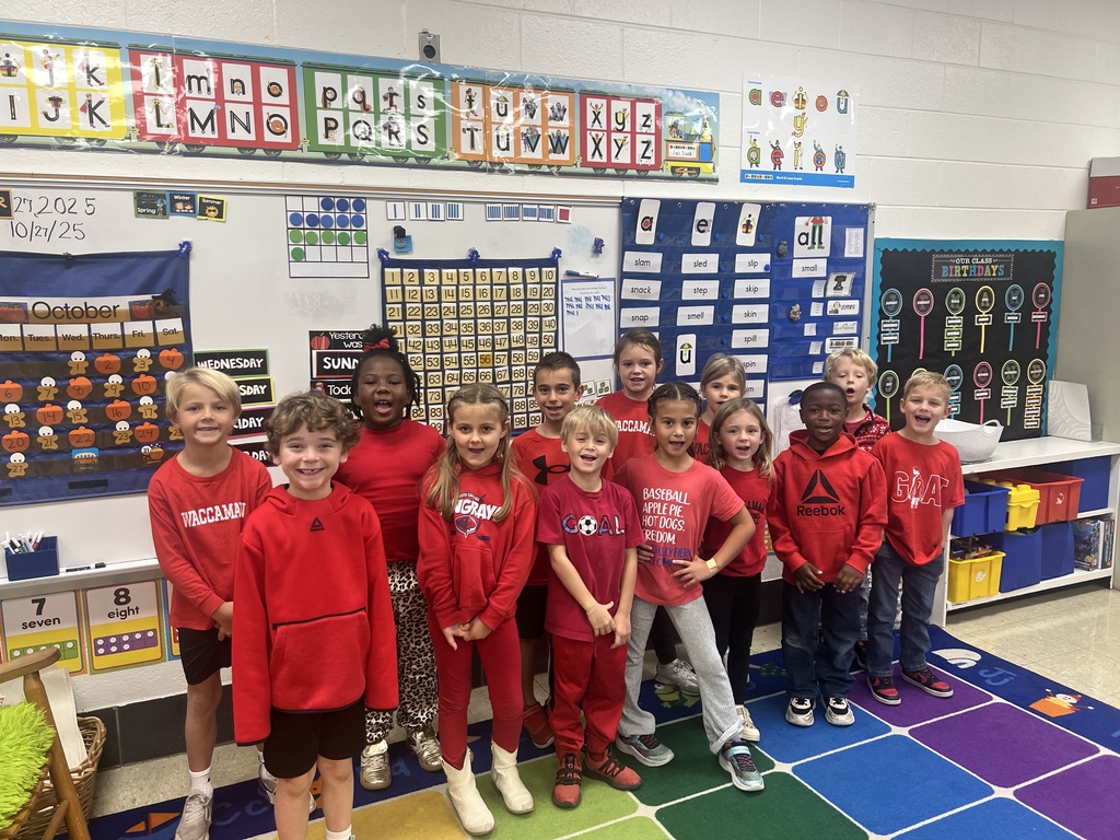 A group of elementary students dressed in red pose together in a classroom for Red Ribbon Week.