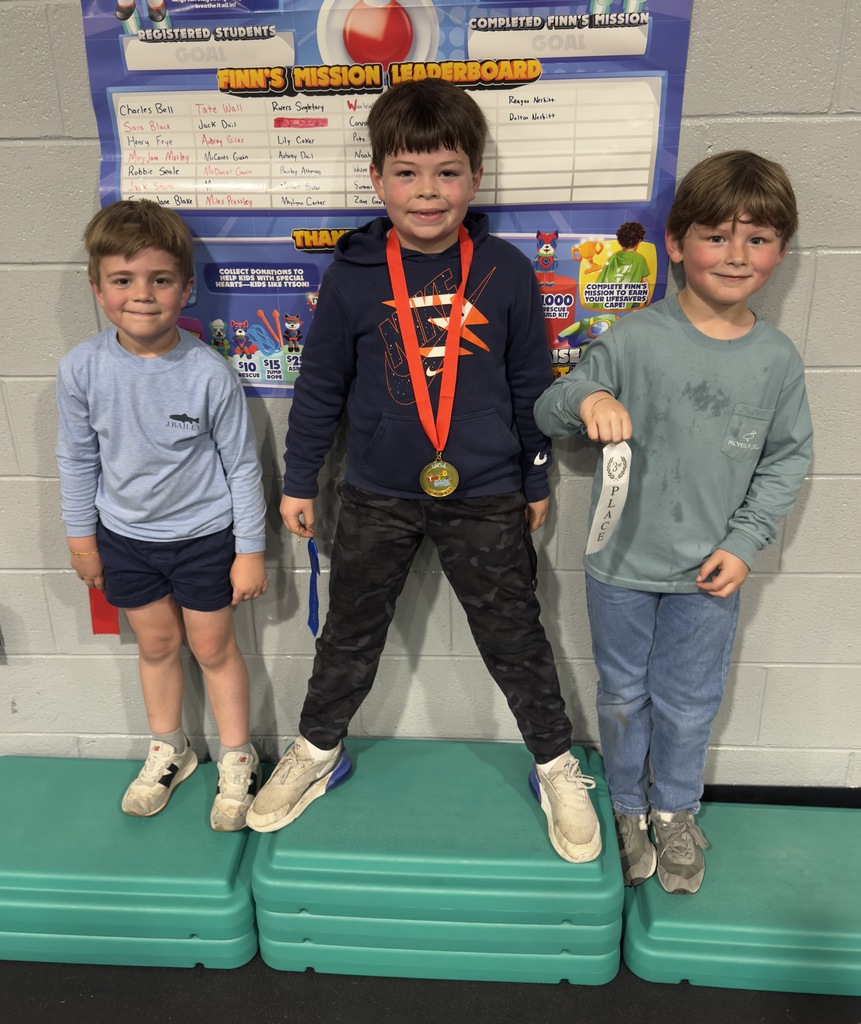 3 boys standing against the wall holding 1st, 2nd, and 3rd Place ribbons for collecting donations for the Kids Heart Challenge 