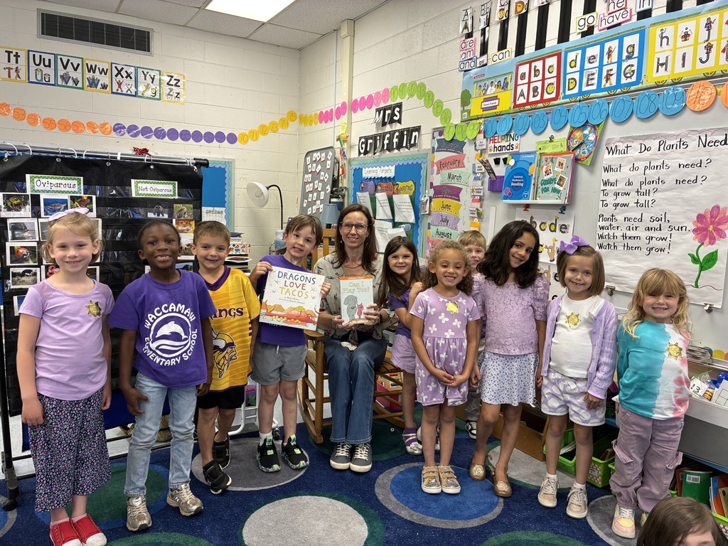 Teacher and students gathered in a classroom, many dressed in purple for Military Child Month.