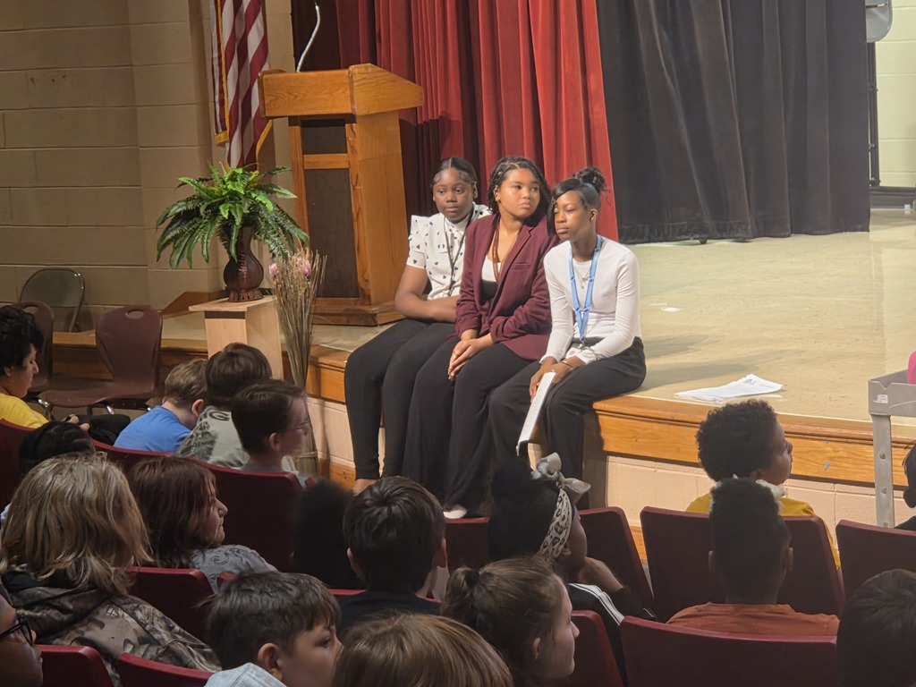 Student Avid Leaders sitting on stage in front of 5th graders.