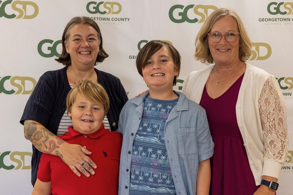 Group photo of a student with family members and school staff at an awards event.