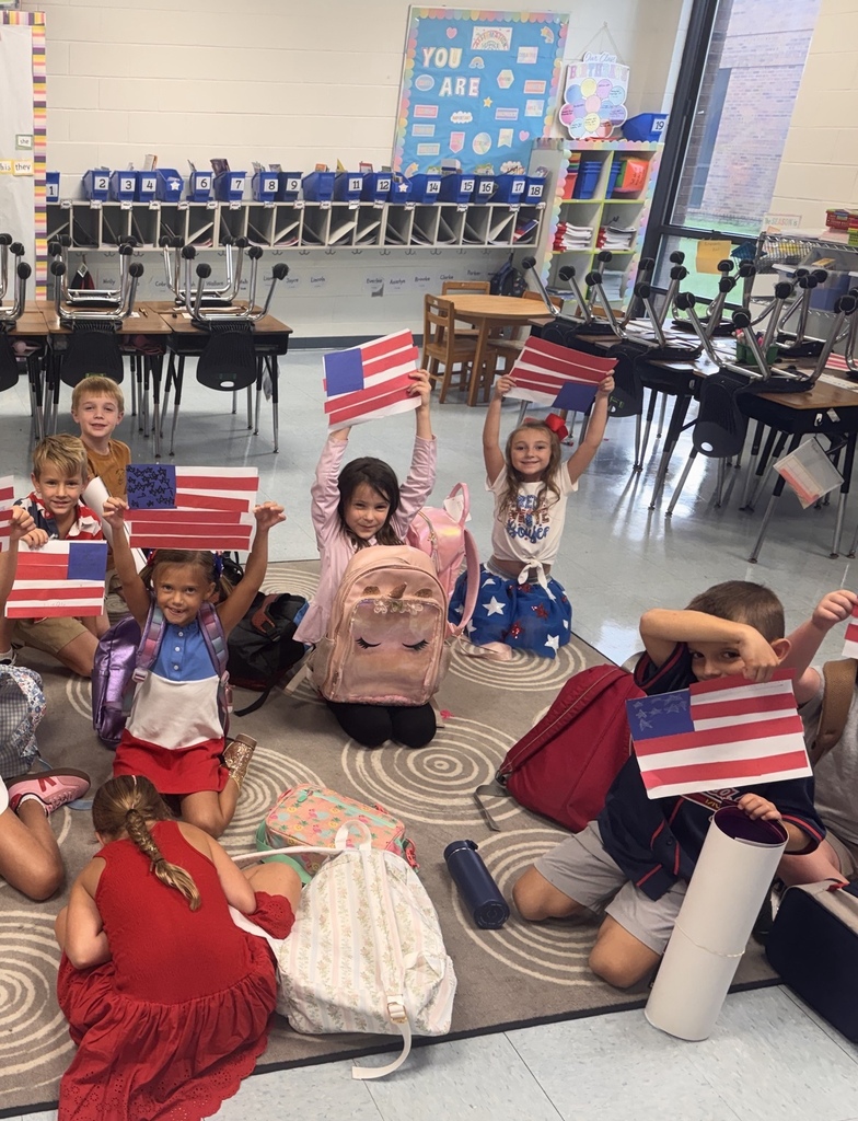 Waccamaw Elementary students display handmade American flags created from red, white, and blue paper during a Patriot Day classroom activity.