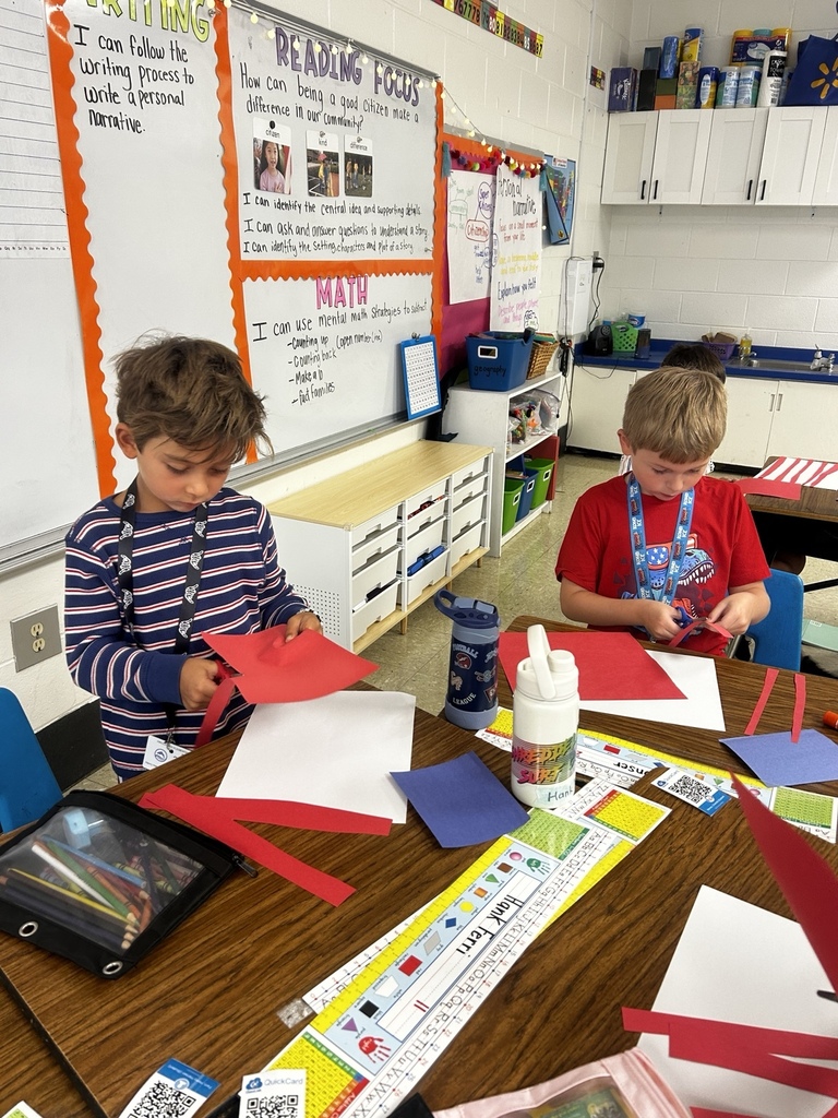 Waccamaw Elementary students dressed in patriotic colors cut red paper strips while creating American flags as part of a Patriot Day classroom activity.