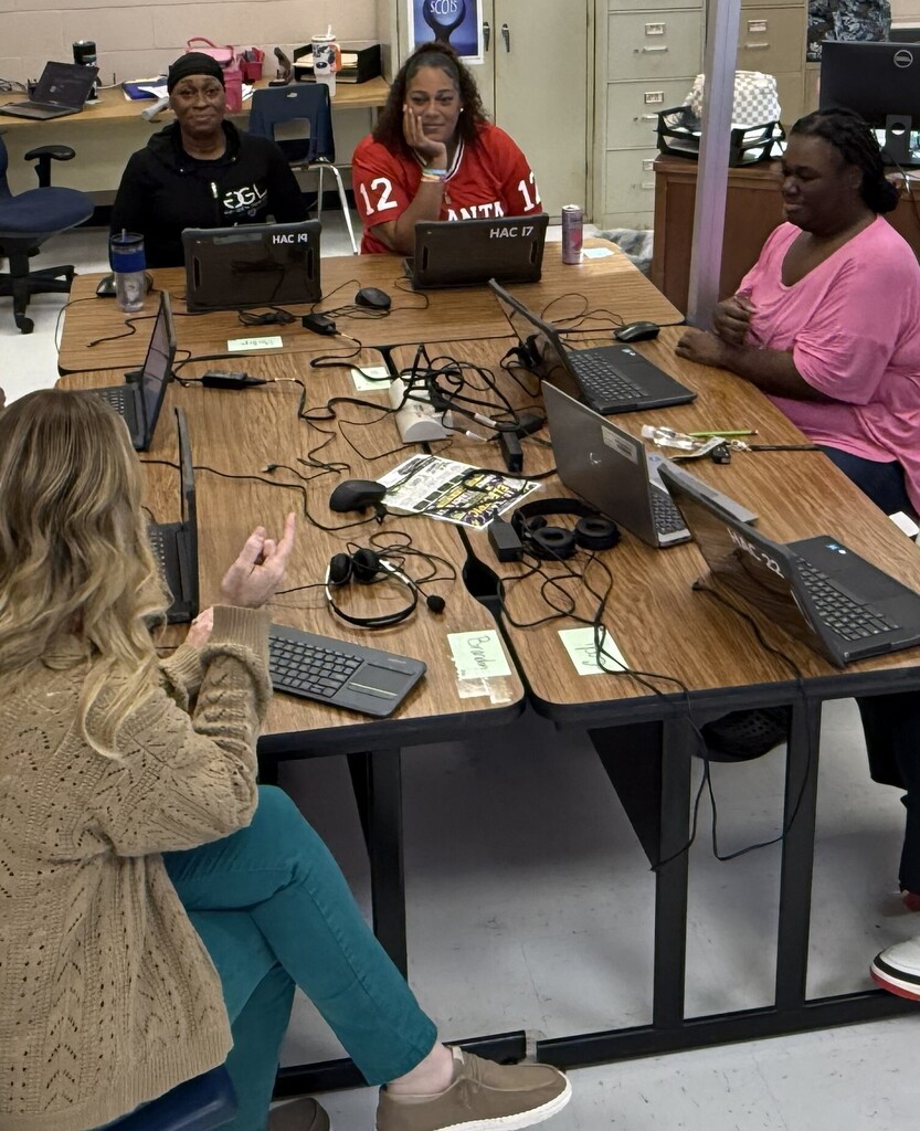 Resume writing workshop in HSD computer lab with teacher and students seated around tables working on laptops.