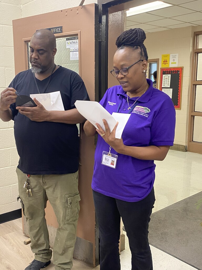 Mr. Travis Alston and Ms. Shannell Greene stand in a hallway at Georgetown County Adult Education, reading their Custodian Appreciation Day cards.