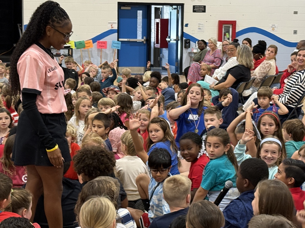 Melissa Jefferson-Wooden stands among a large group of Waccamaw Elementary students during the assembly as students participate and raise their hands.