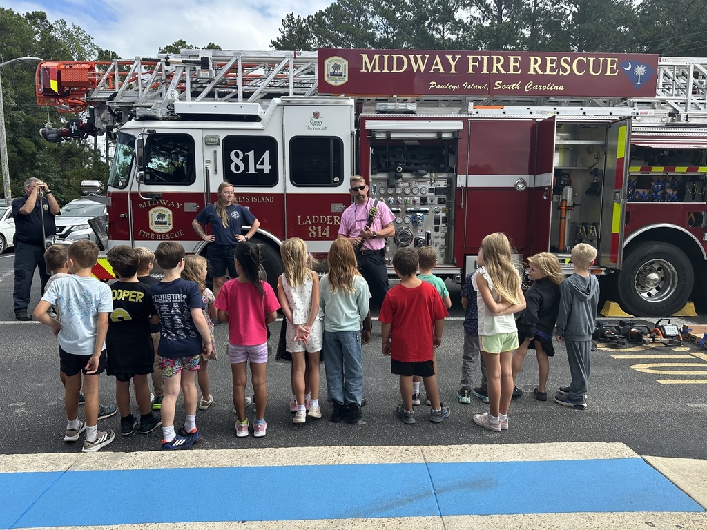 Waccamaw Elementary students listen as Midway Fire Rescue firefighters explain the features and equipment of a ladder truck during the outdoor portion of their fire safety visit.