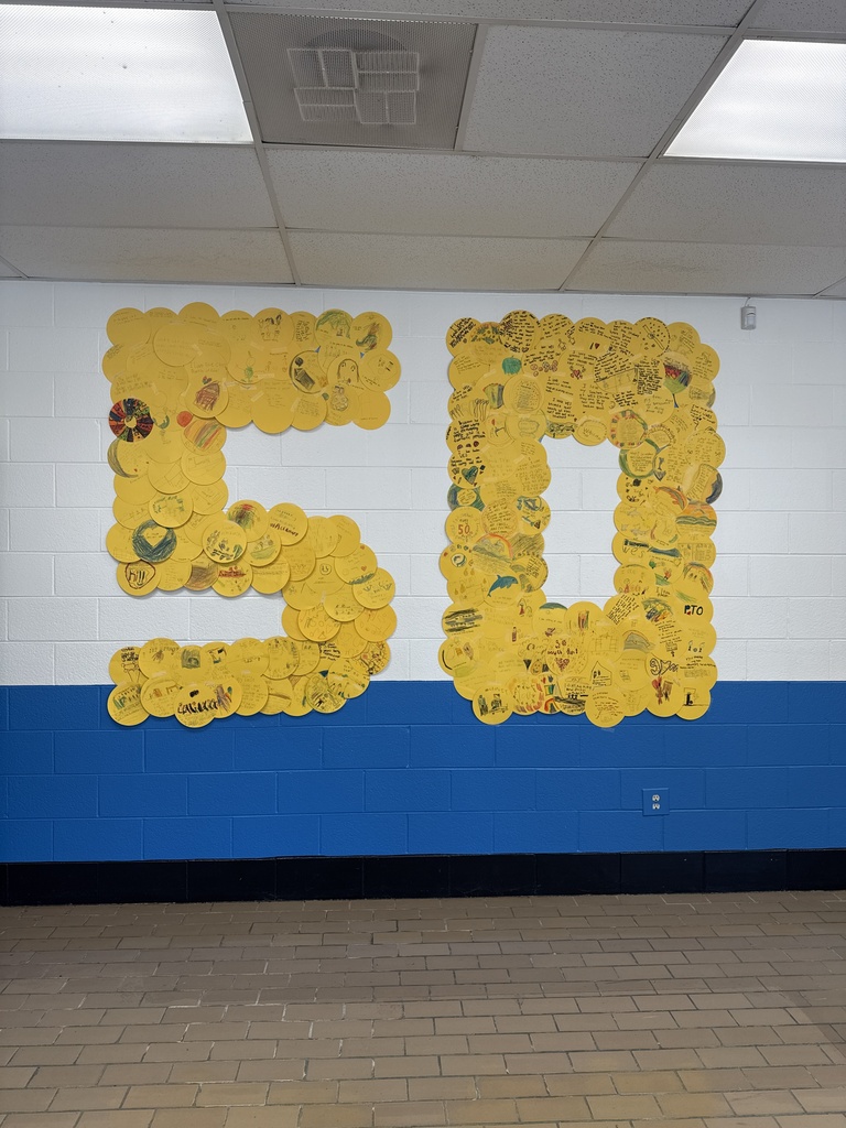 A large number 50 created from gold circles is displayed on a school hallway wall.