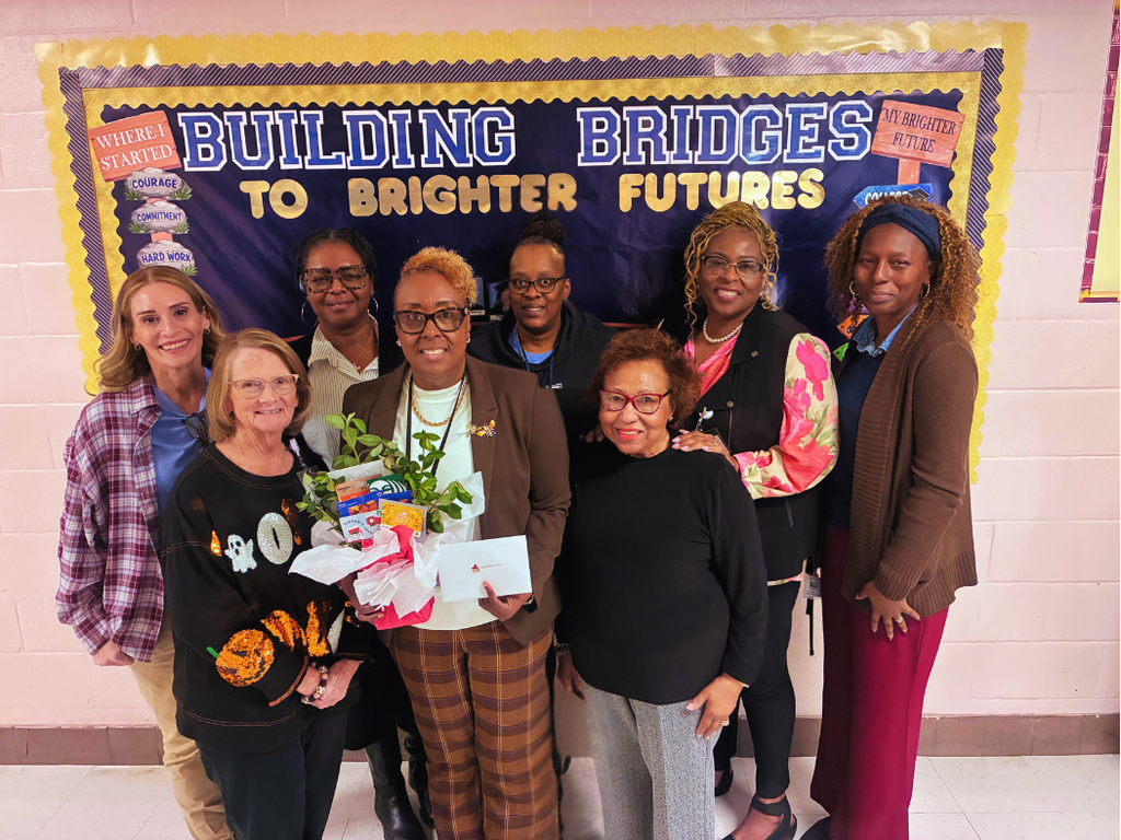 Happy Boss’s Day to Dr. Paula Anderson! Members of our GCAE team gathered to celebrate Dr. Paula Anderson, in the center of the front row holding a gift basket with a plant and a card.