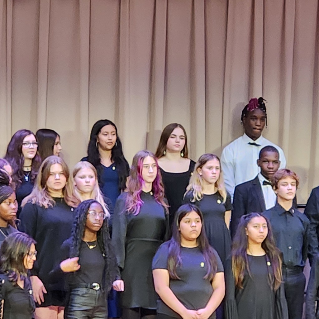 Carvers Bay Middle STEAM students singing on stage dressed in black and white performance attire.