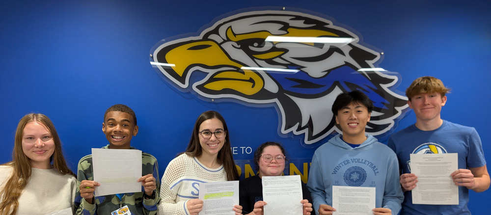 Six Germantown High School Students stand holding press release after learning the Best Buddies group had been named the winner of the first-ever Unified 2026 Challenge through Special Olympics Wisconsin.