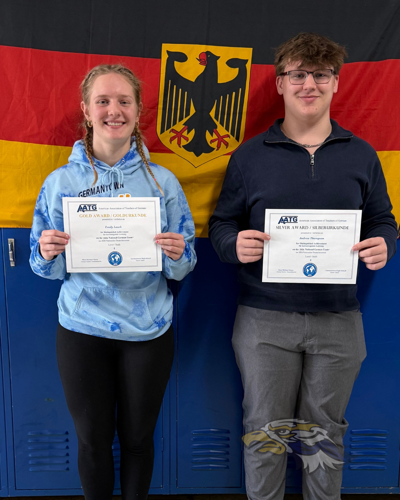 Andrew Thompson and Emily Laack hold certificates recognizing their performance on the 2026 National German Exam, standing in a high school hallway with a German flag in the background.