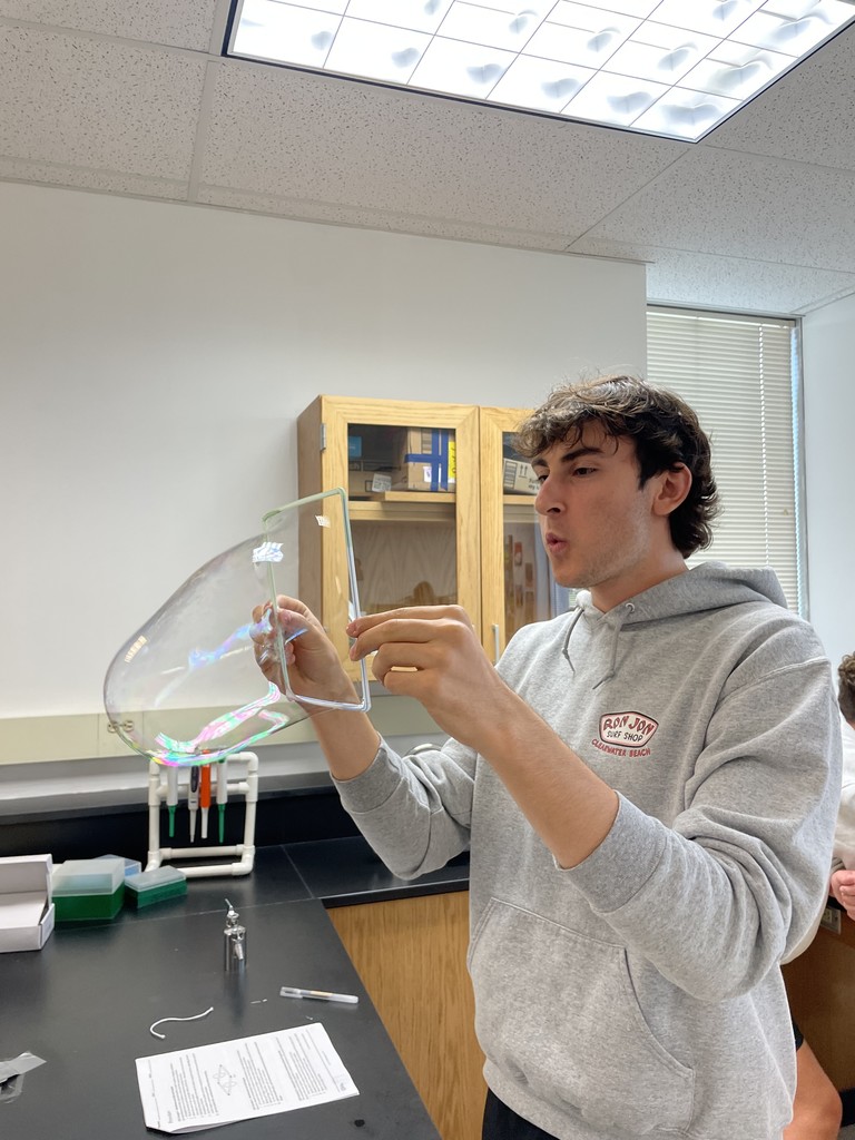 A student blows up a bubble in AP Biology class learning how they relate to the cell membranes students are learning about in class.