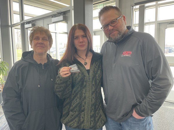 A student holds up her academic pin joined by her family following the ceremony.