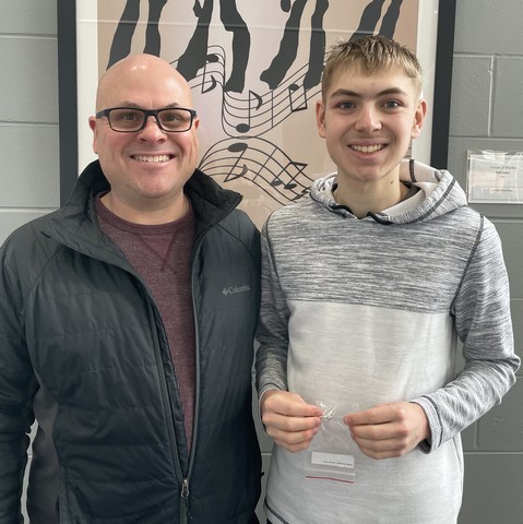 A student holds up his academic letter joined by family following the ceremony.