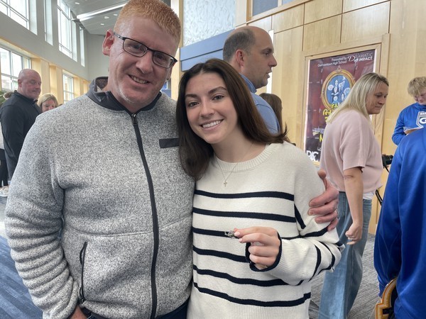 A student holds up her academic pin joined by her family following the ceremony.