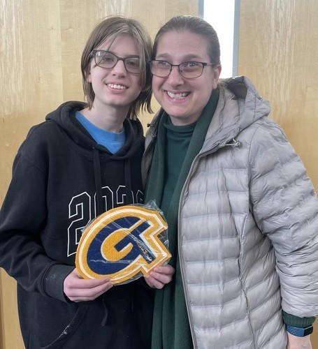 A student holds up an academic letter joined by family following the ceremony.